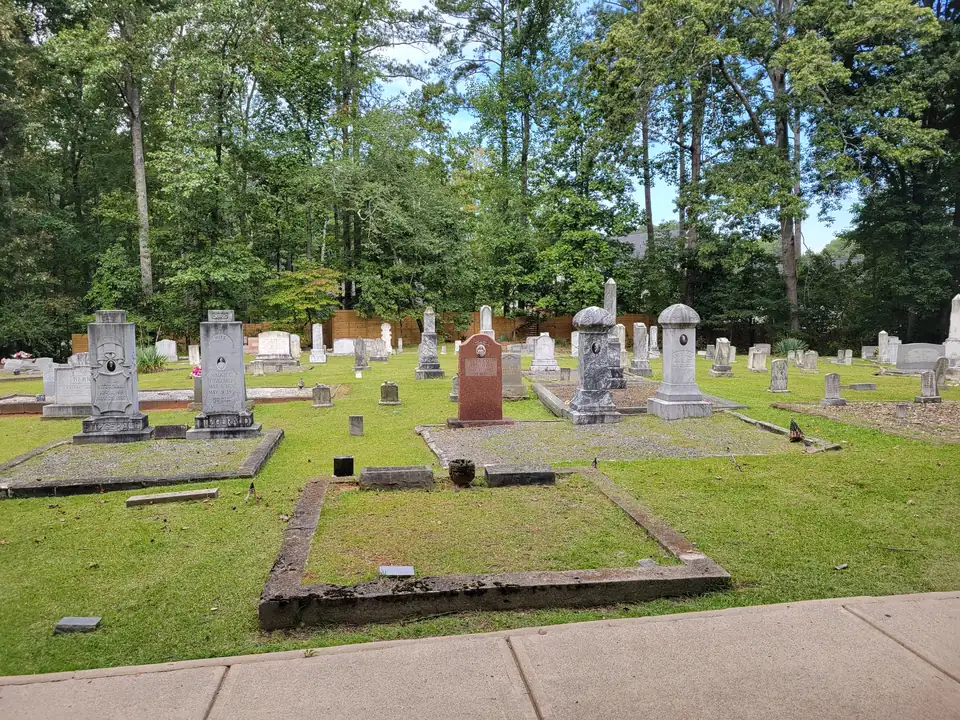 Old cemetery with granite family plots, tall carved headstones (Fitzgerald family stones legible), small flags, mown grass and tall trees